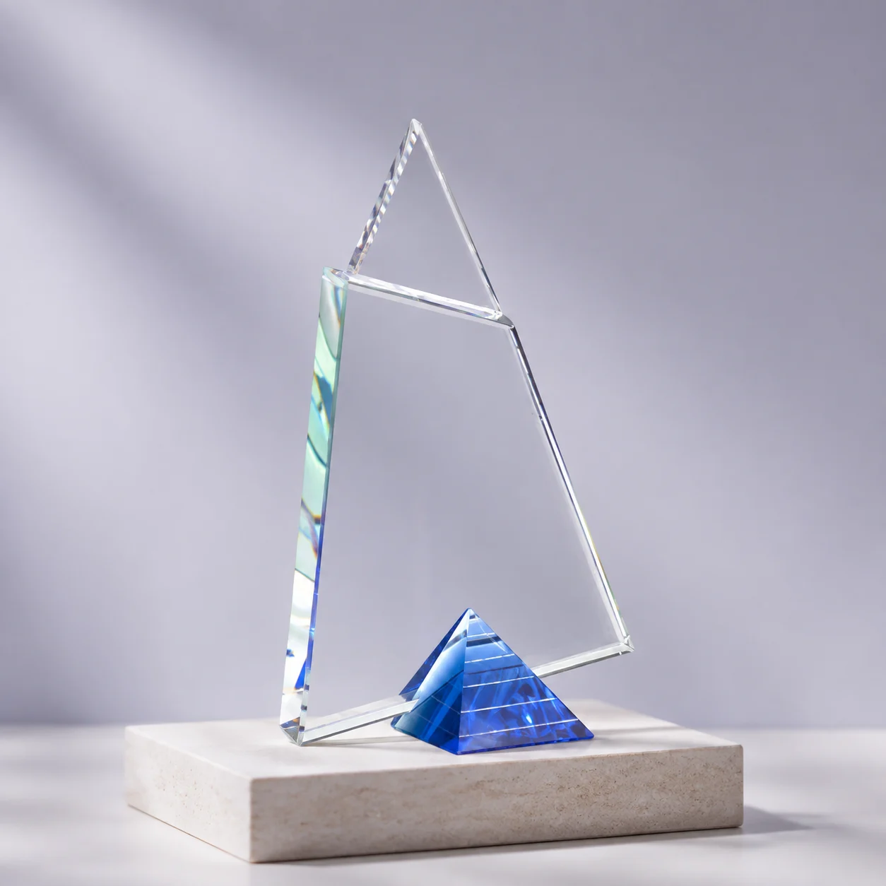 Crystalic's geometric clear crystal award with a blue pyramid base, presented on a stone plinth