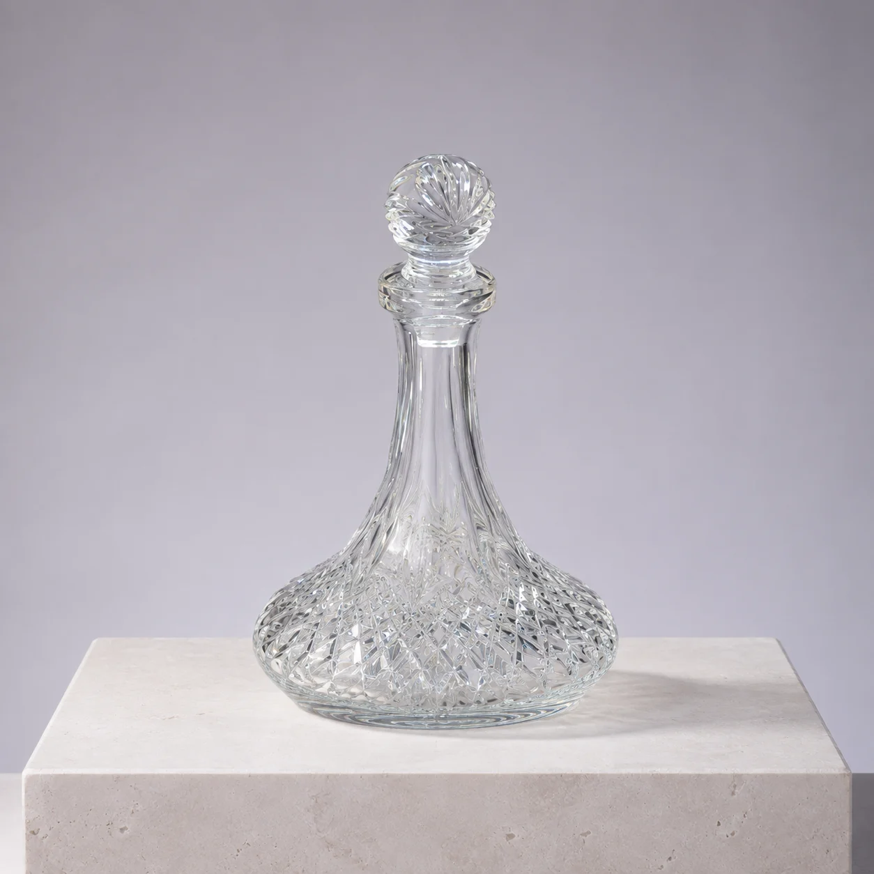 Faceted cut crystal decanter with a diamond-cut base and spherical stopper, a corporate gift